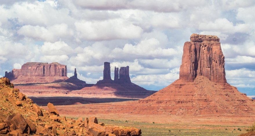 Red sandstone buttes rising from a desert valley under a cloudy sky